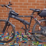 Image of a bike with a battery pack strapped to its rack, and dozens of colorful vape shells tossed onto the ground around it.